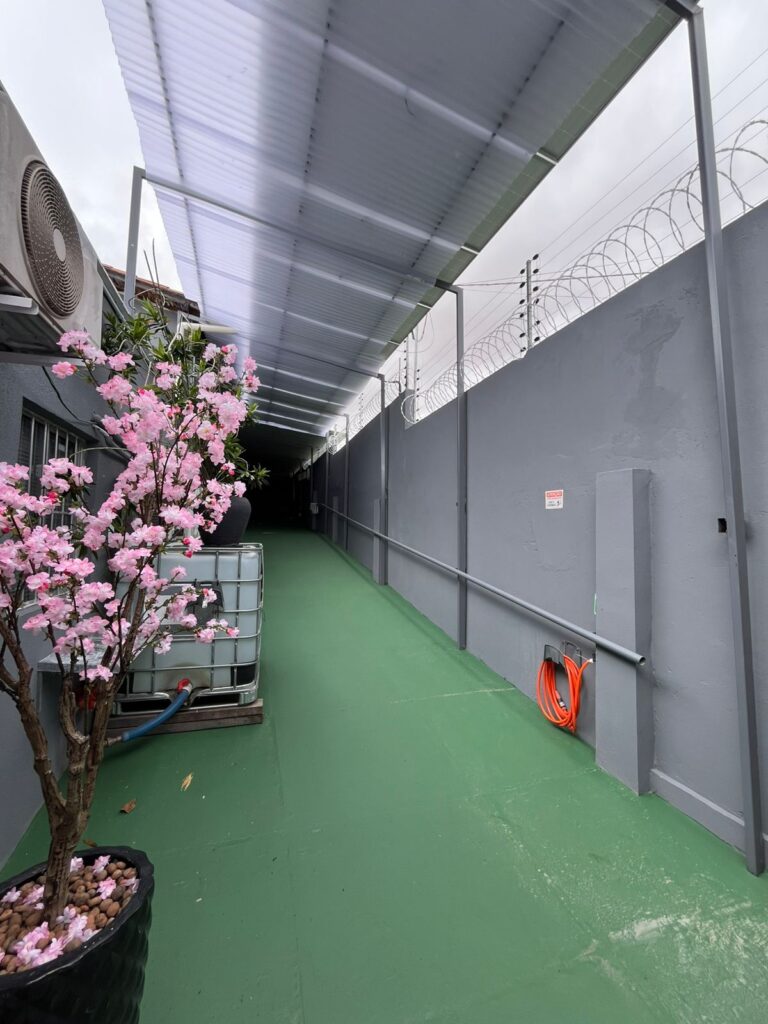 Área externa coberta com piso verde e corrimão